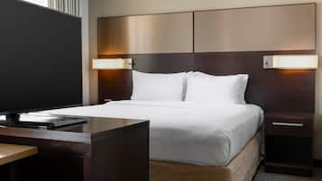 A hotel room with a large bed, bedside tables, a desk, and a flat-screen TV.