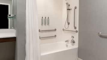 Un baño moderno con bañera, ducha y barras de apoyo.