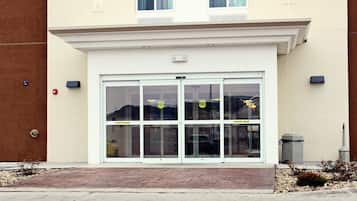 A building entrance with a glass door and a brick pathway leading to it.
