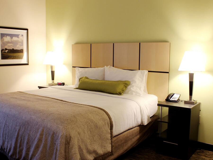 A hotel room with a bed, two bedside tables with lamps, a framed picture on the wall, and a telephone on one of the tables.