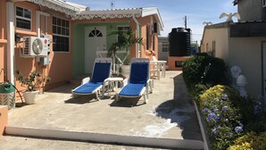 A small outdoor lounge area with two sun loungers, a table, and chairs. - Hopeville Apartments (Charnocks)
