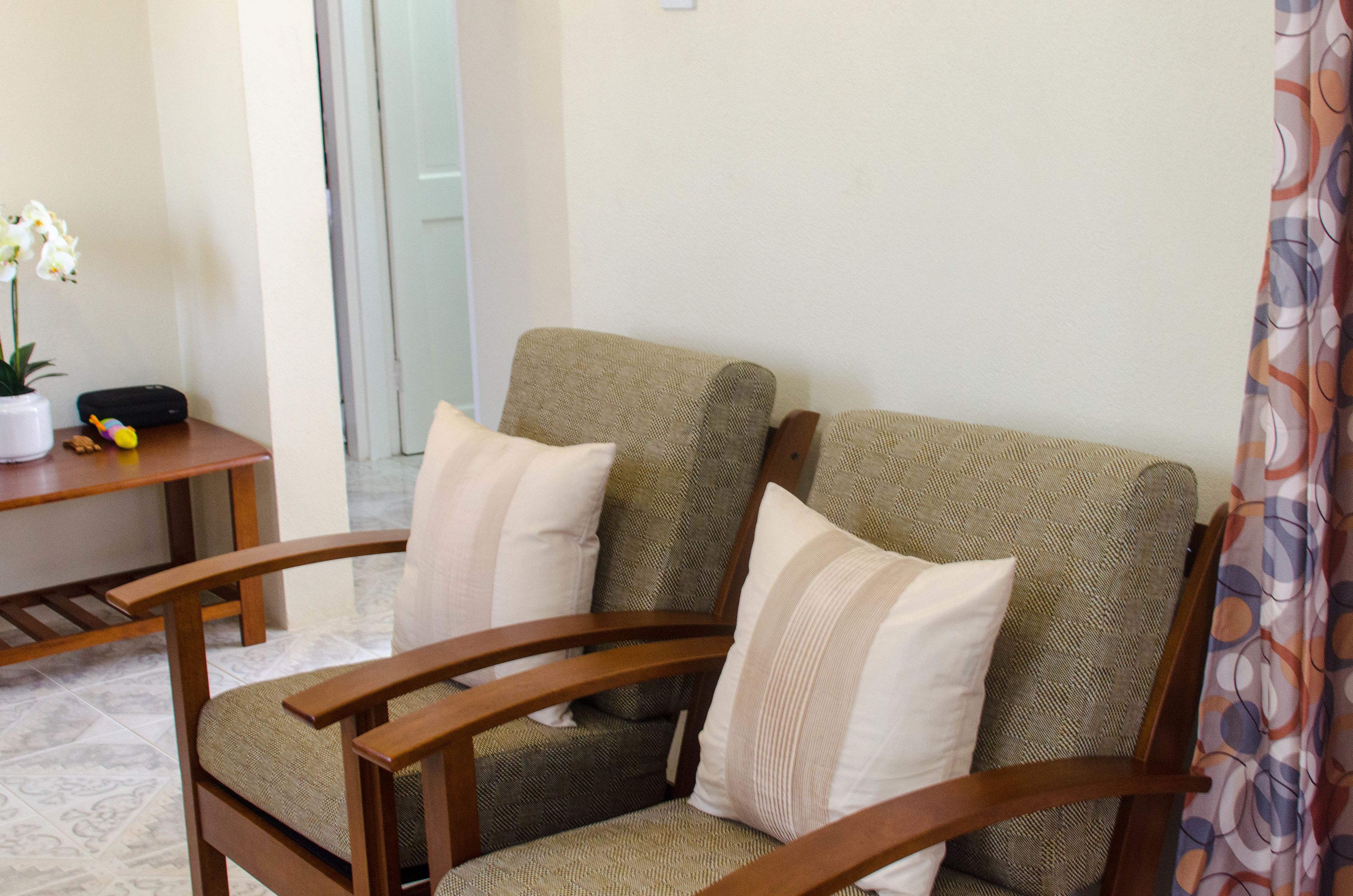 A wooden armchair with a woven seat and backrest, accompanied by two pillows.