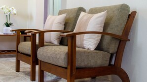 A wooden armchair with a woven seat and backrest, accompanied by matching cushions. - Hopeville Apartments (Charnocks)