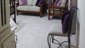 A room with a sofa and two chairs, a painting on the wall, and curtains. - Hopeville Apartments (Charnocks)