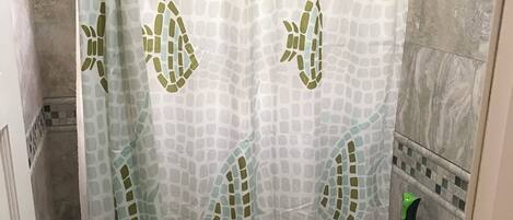 A bathroom with a shower curtain featuring a leaf pattern, a toilet, and a sink.