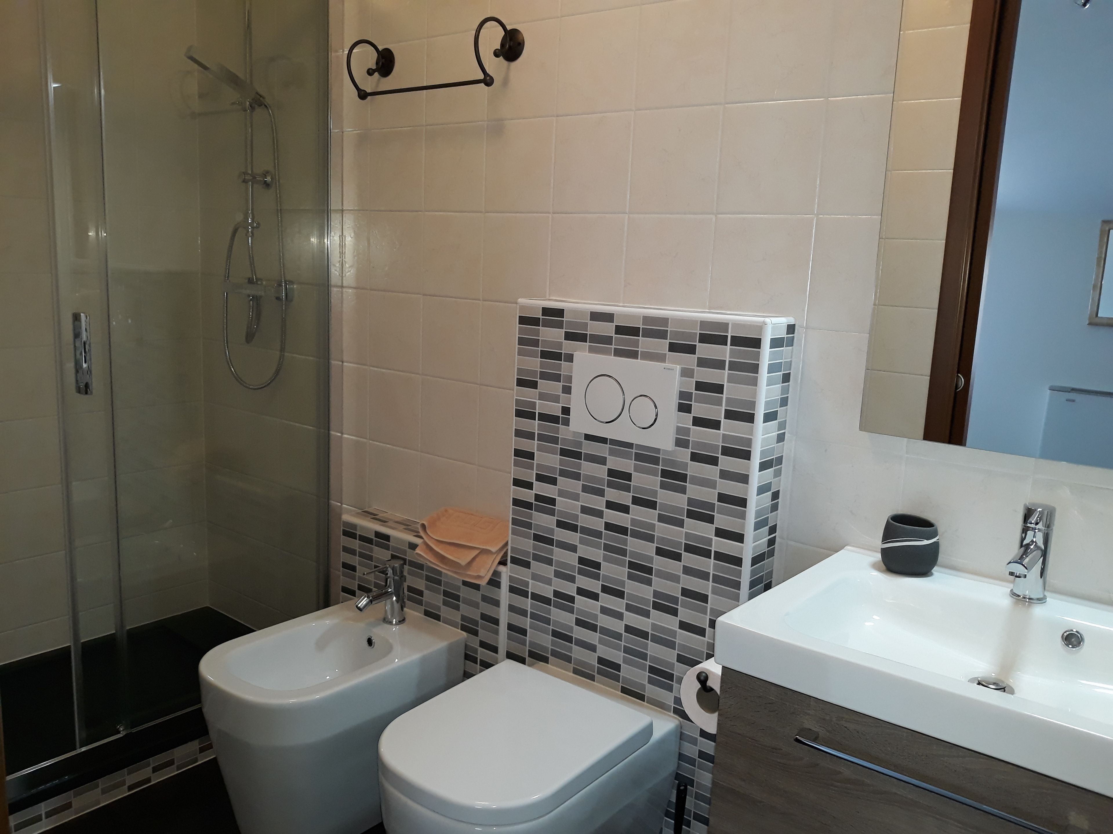 Un baño con ducha de vidrio, lavamanos blanco y retrete.