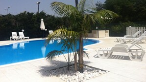 Una piscina con lettini bianchi e una palma.