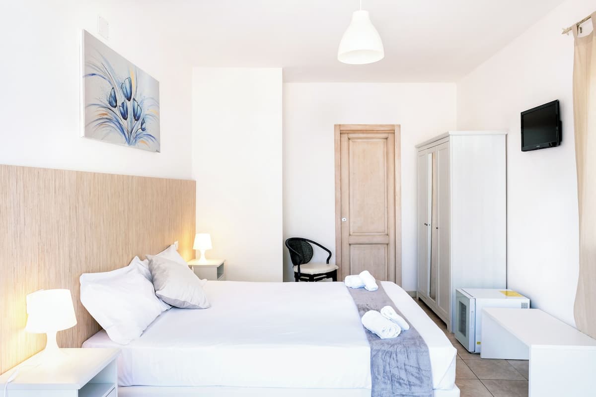 Een hotelkamer met een bed, een bureau, een stoel, een kast en een televisie.