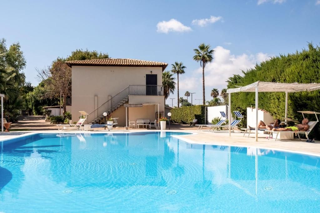 A swimming pool with lounge chairs and a building with a staircase.