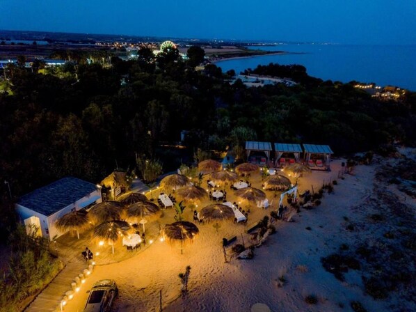 A beachside resort with thatched umbrellas and a paved walkway leading to a building. - Hotel Aria di Mare (Ragusa)