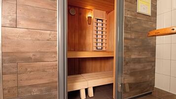 Eine Sauna mit Holzwänden und -bänken, einer Wanduhr und einer Saunatür.