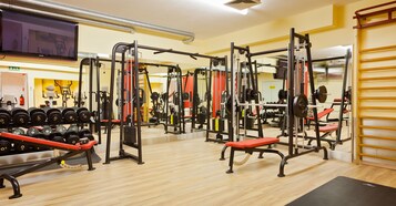 Uma academia com diversos equipamentos de exercícios, incluindo aparelhos de musculação e halteres.