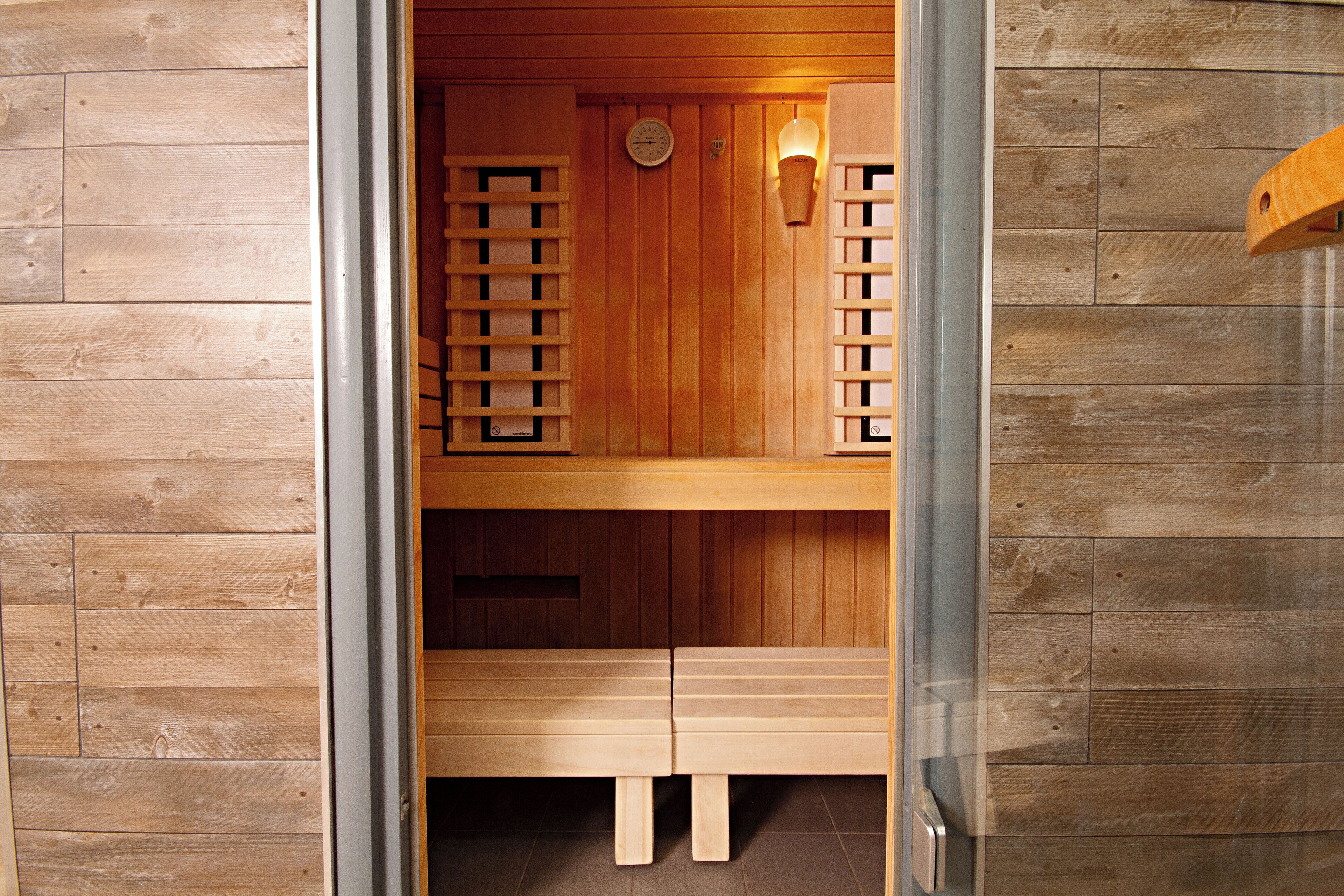 Una sauna con bancos de madera y un reloj en la pared.