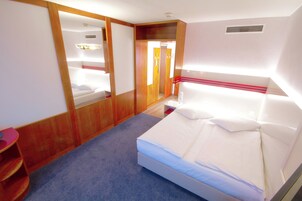 Quarto com cama, guarda-roupa de madeira e espelho.