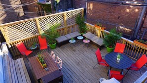 A wooden deck with a built-in seating area, a barbecue grill, and outdoor tables and chairs.