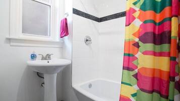 A bathroom with a white sink, a shower curtain, and a bathtub.