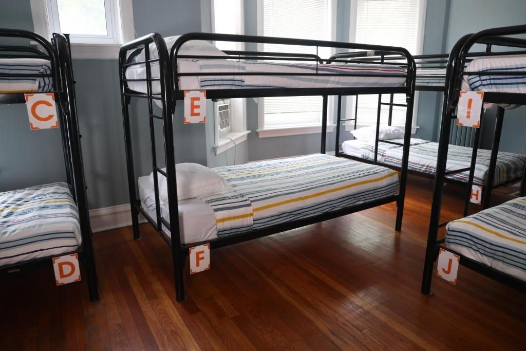 A dormitory room with bunk beds labeled C, E, F, and J.