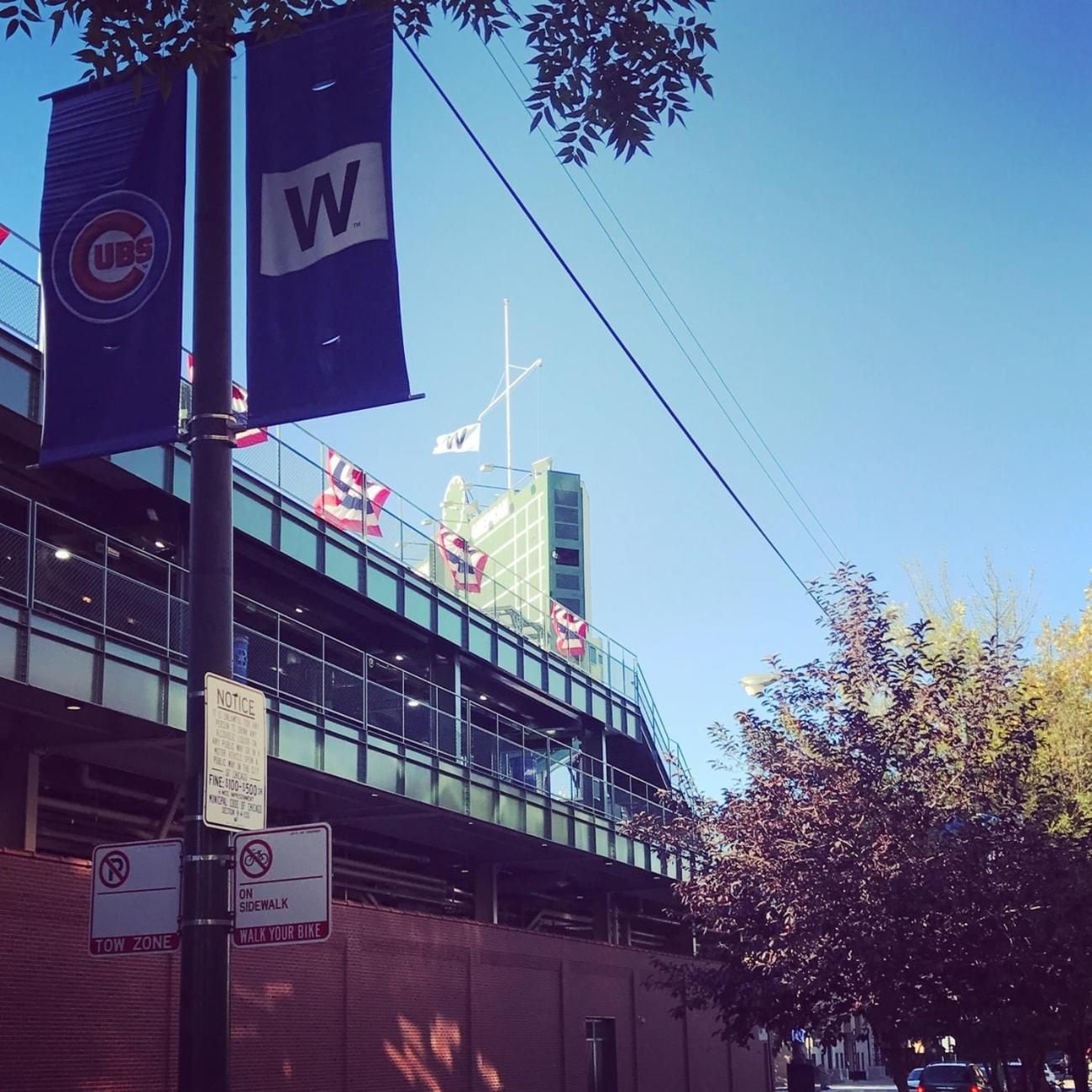 A building with a glass facade, a sign indicating a tow zone, and a flag with the letter 'W' on a flagpole.
