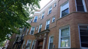 A row of brick townhouses with large windows and a central entrance.