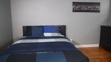 Ein Schlafzimmer mit einem Bett, einem Stadtbild an der Wand und einer Kommode.