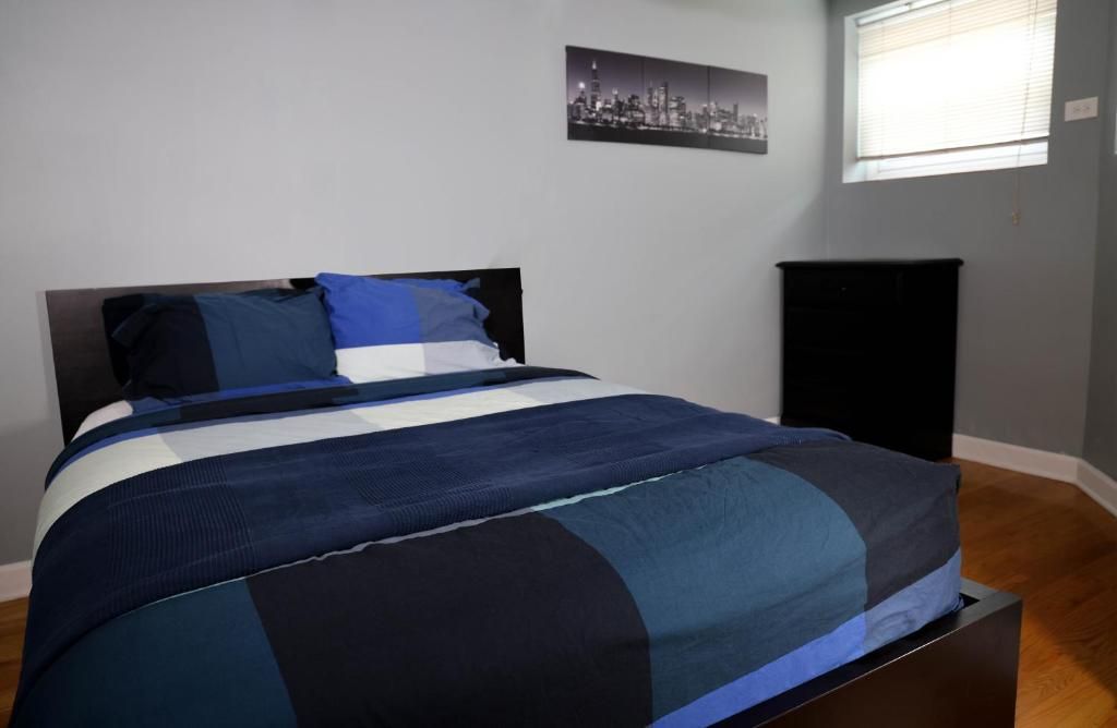 Quarto com uma cama, um armário preto e uma fotografia de uma vista urbana na parede.