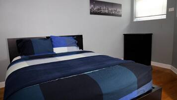 Quarto com uma cama, um armário preto e uma fotografia de uma vista urbana na parede.