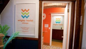 A hallway with a sign for Wrigley Hostel Chicago, including address and contact information.