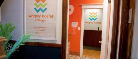 A hallway with a sign for Wrigley Hostel Chicago, including address and contact information.