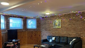 A cozy living room with a brick wall, wooden floor, and a sectional sofa.