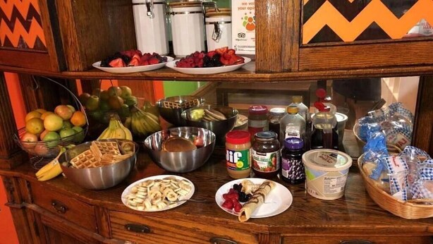 A buffet table with various food items including fruits, waffles, and condiments.