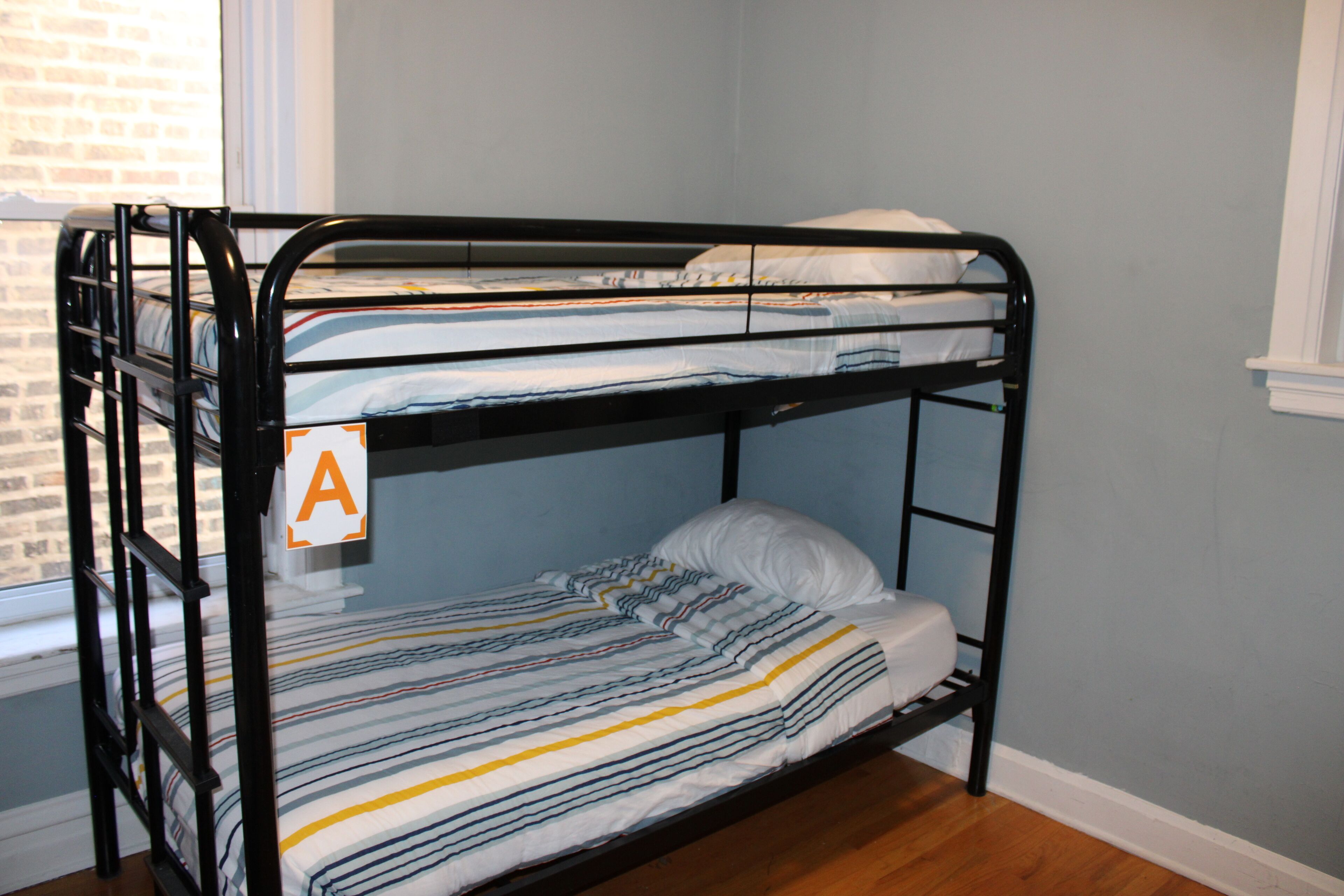 A bunk bed with a striped bedspread and a pillow, labeled with an 'A' sign.
