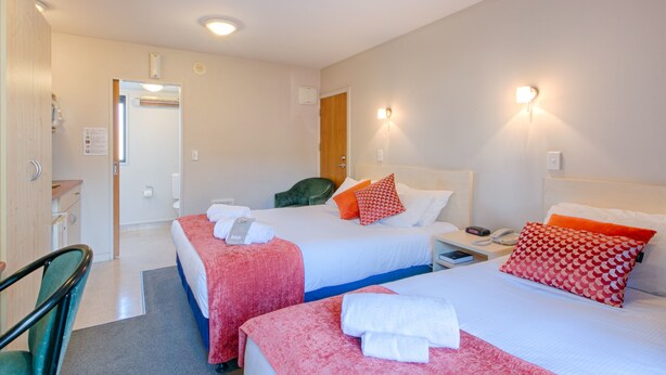 Een hotelkamer met twee bedden, een bureau en een stoel.