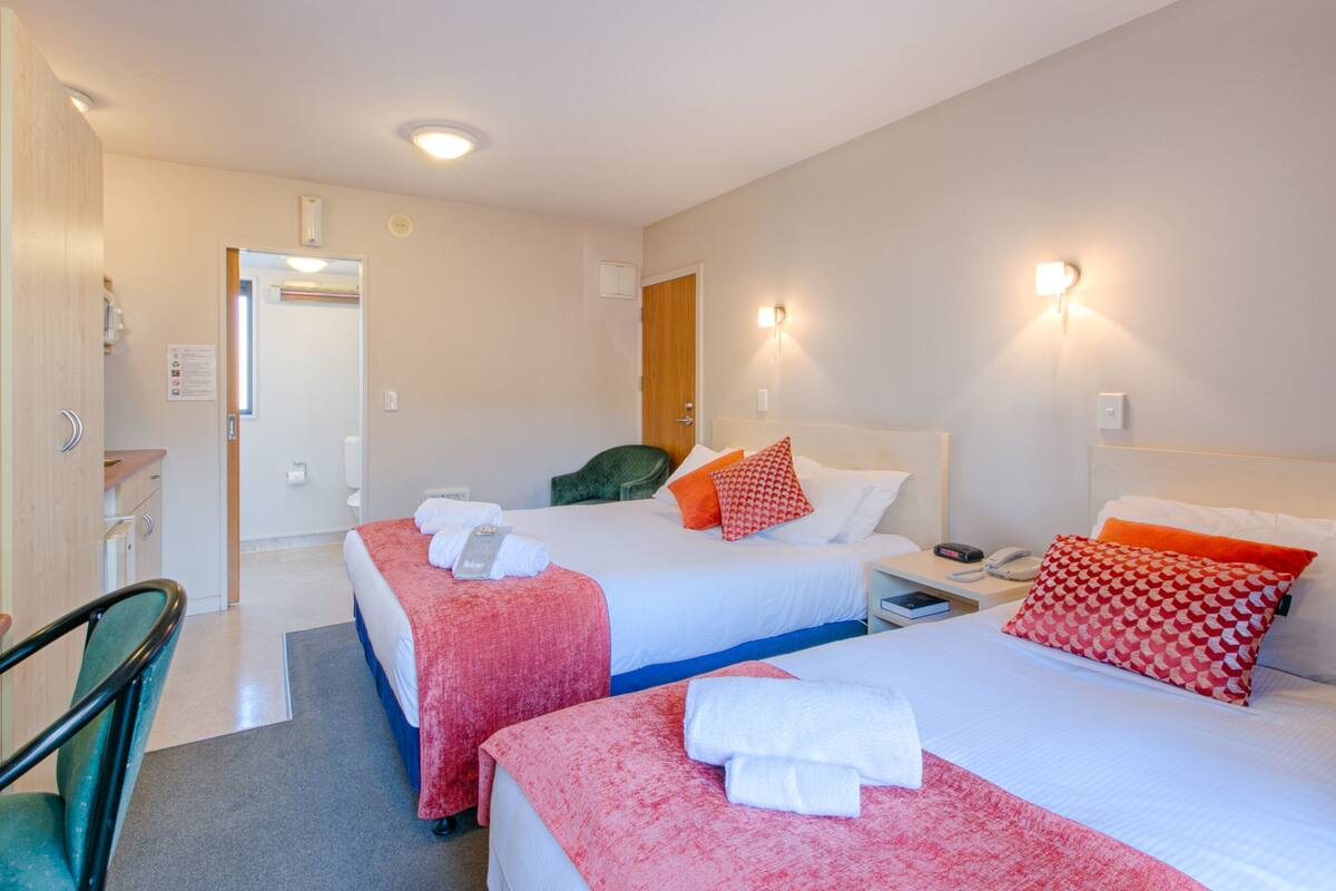 Une chambre d’hôtel avec deux lits, un bureau et une chaise.