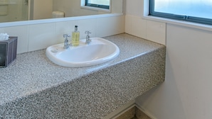 Een badkamer met een wit wastafelmeubel, een spiegel en een raam.