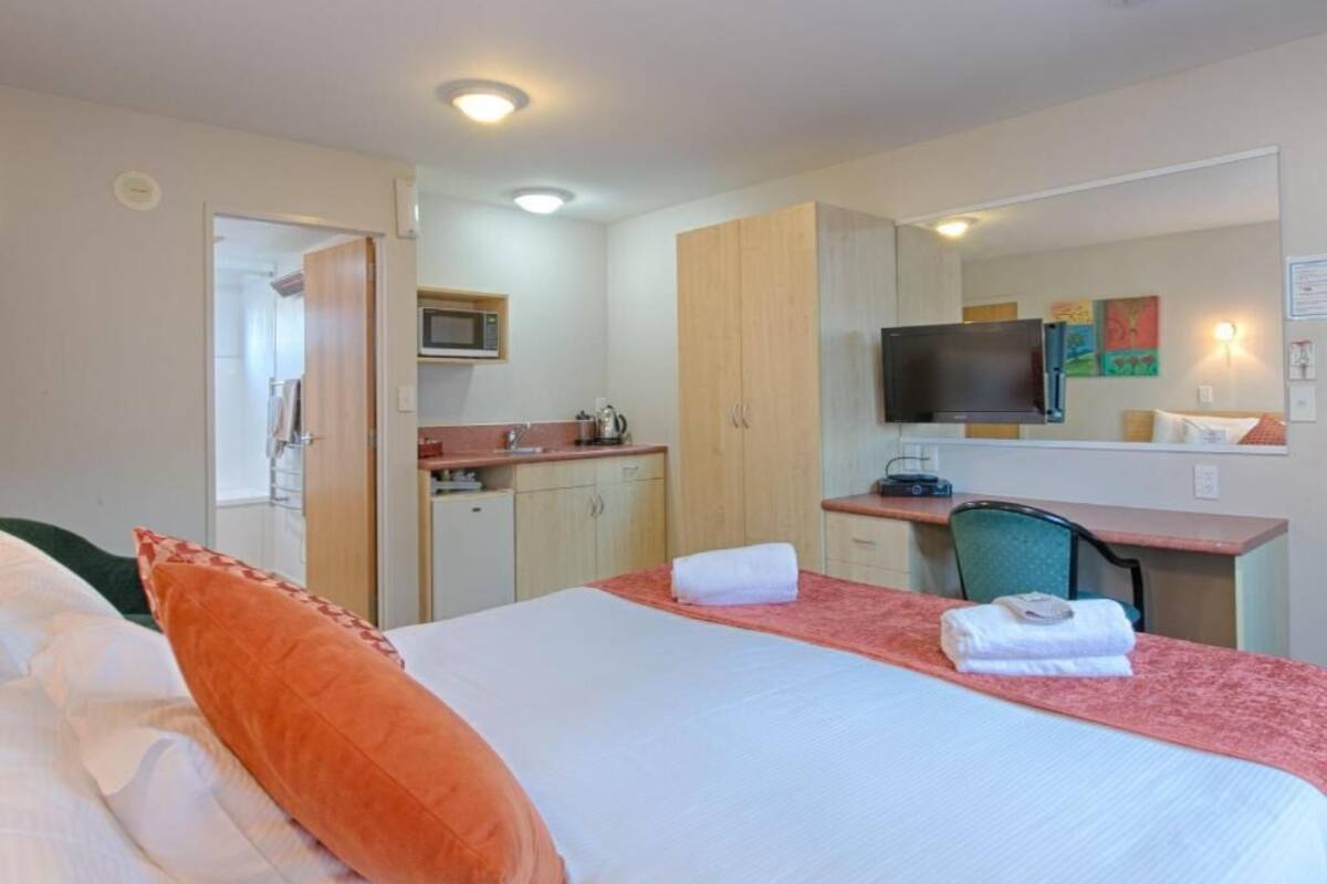 Une chambre d’hôtel équipée d’un lit, d’un bureau, d’un four à micro-ondes, d’une télévision et d’une kitchenette.