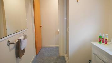 A bathroom with a white sink, a mirror, and a towel rack. There are three bottles of shampoo on the sink.