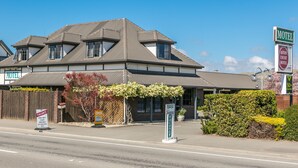 A motel with a two-story structure, a covered parking area, and a sign indicating availability. - Aston Court Motel Blenheim (Blenheim)