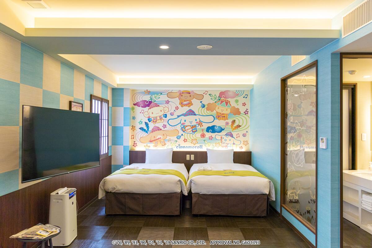 A hotel room with two beds, a TV, a large window, and a colorful wall mural.