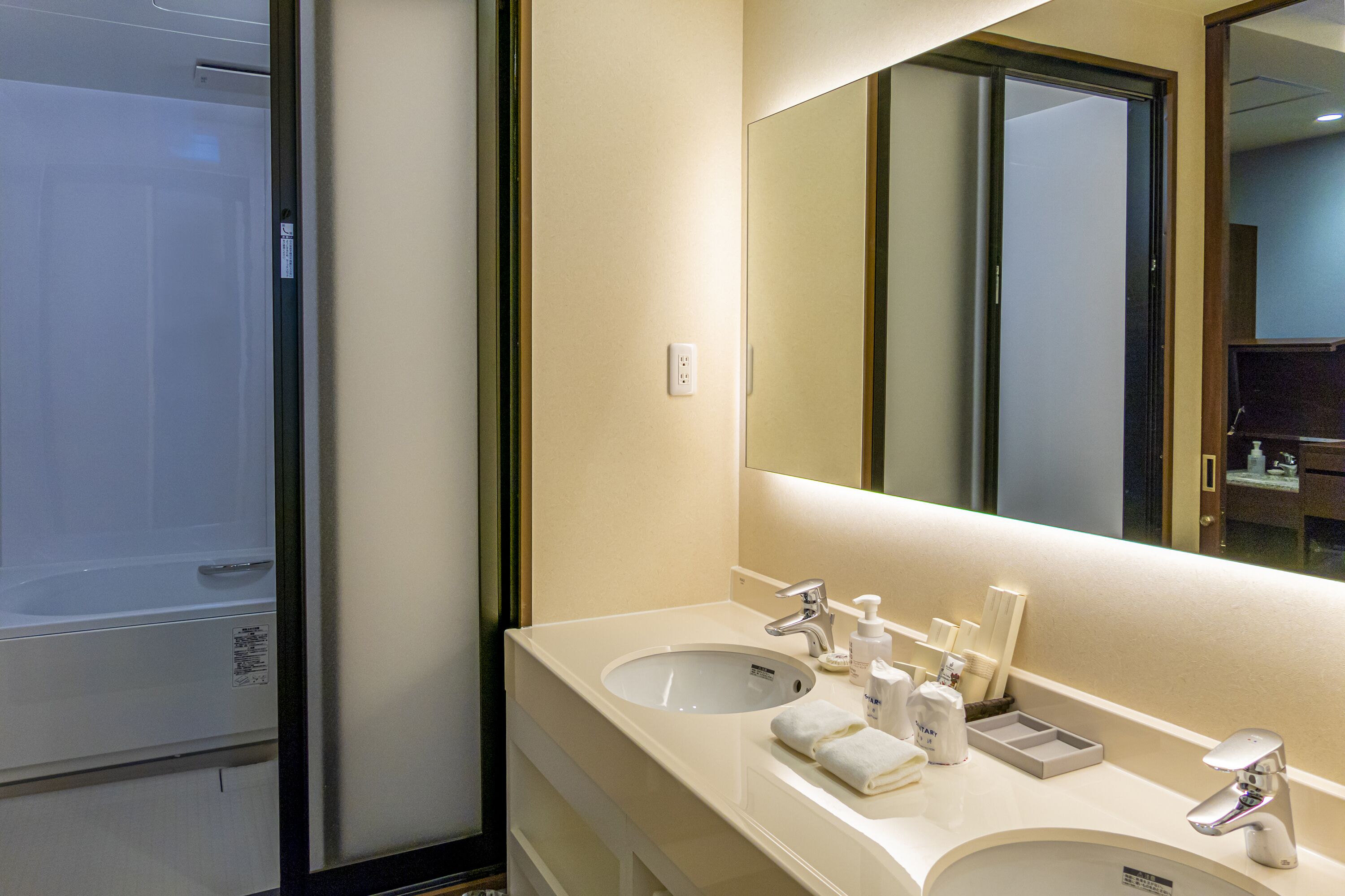 Un baño de hotel con un espejo grande, dos lavamanos y una ducha.