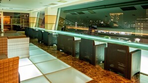 Een moderne hotel lobby met zithoeken, een glazen balustrade en uitzicht op de stad 's nachts.