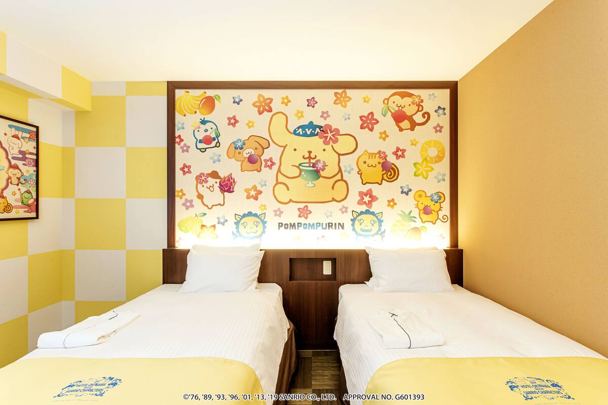 A hotel room with two beds, a checkered wall pattern, and a colorful wall mural.