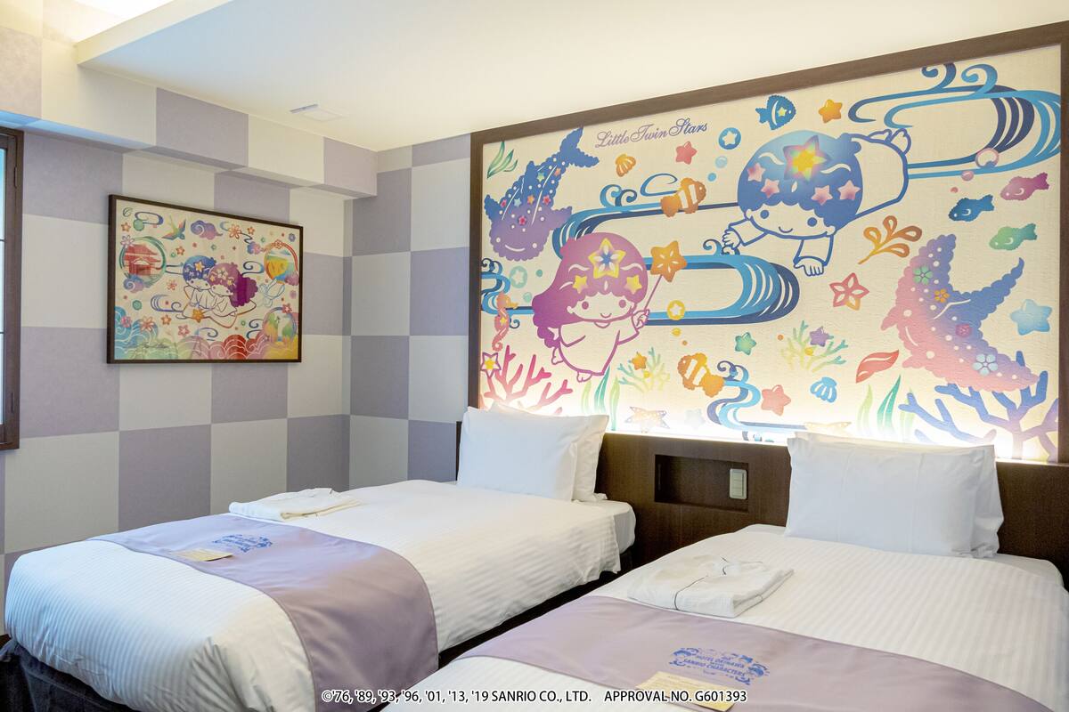 A hotel room with two beds, a checkered wall, and a colorful mural.