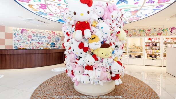 Een grote Hello Kitty presentatie in een hotellobby, met een kleurrijk plafond en een bordje 'Hotel Okinawa with Sanrio Characters'.