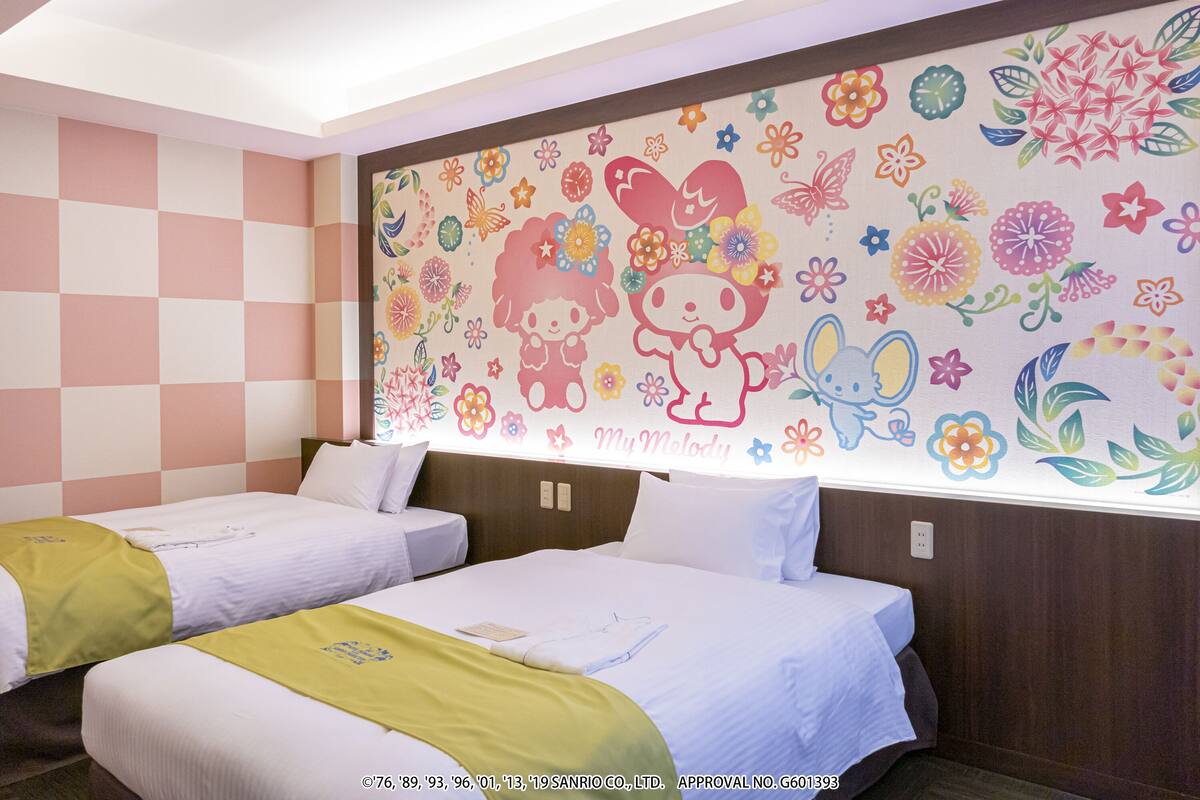 A hotel room with two beds, a checkered wall, and a floral mural.