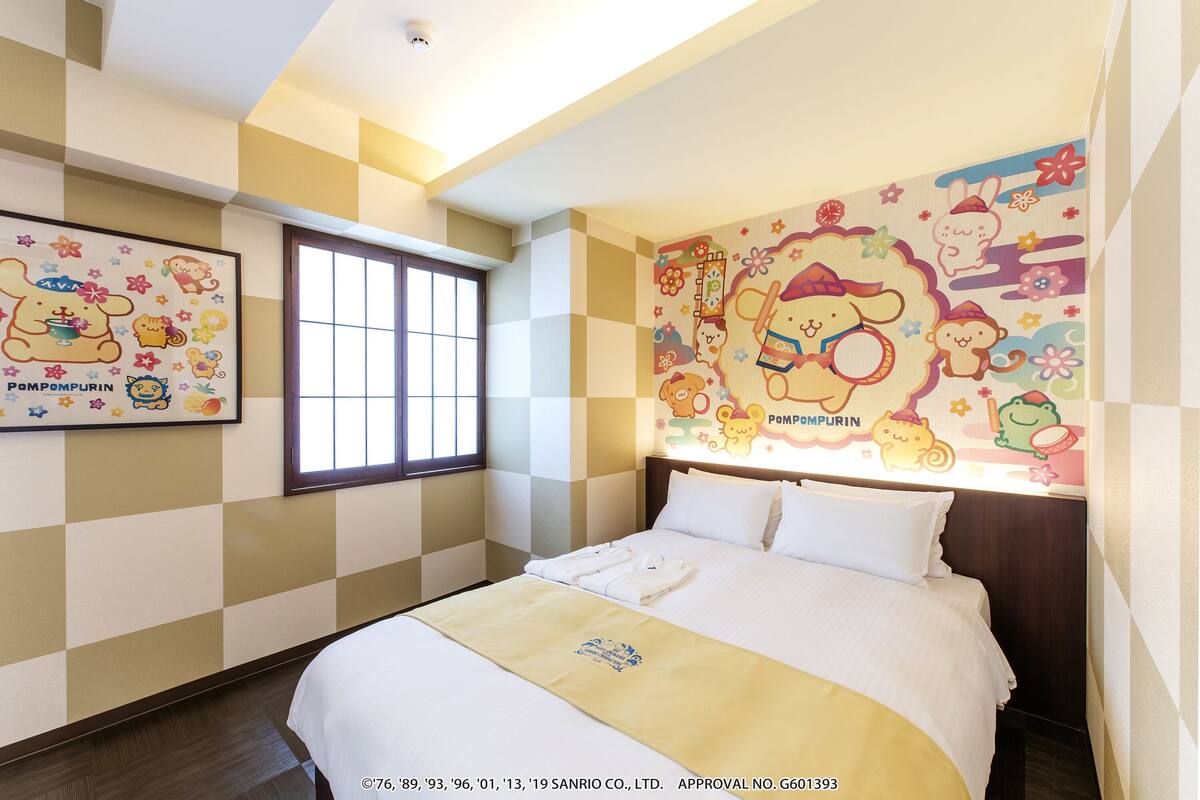 A hotel room with a checkered wall pattern, a large window, and a mural with cartoon characters.