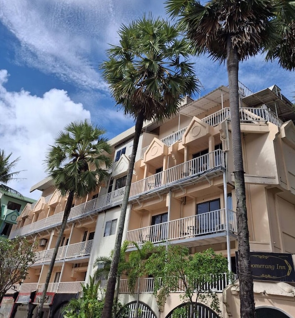 A multi-story hotel with balconies, palm trees, and a clear sky. - Boomerang Inn (Patong)