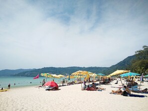 A beach with umbrellas and people sunbathing. - Boomerang Inn (Patong)