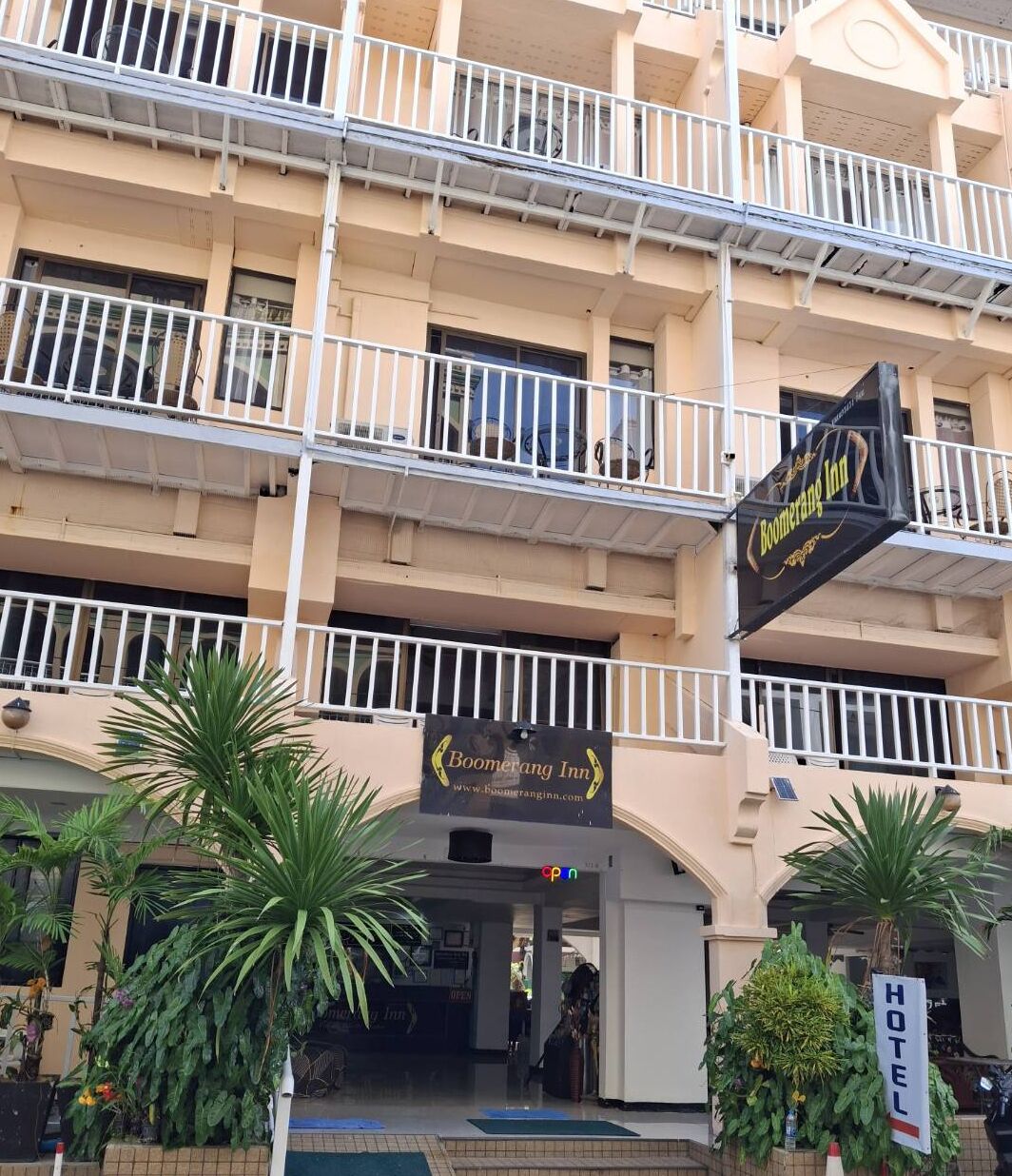 Un hotel de varios pisos con balcones, un llamativo letrero que dice 'Boomerang Inn' y un letrero que indica 'HOTEL'.