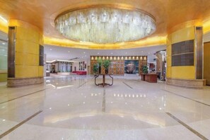 A spacious lobby with a central chandelier, a reception desk, and a decorative wall with circular patterns. - Huaan International Hotel (Shenzhen)