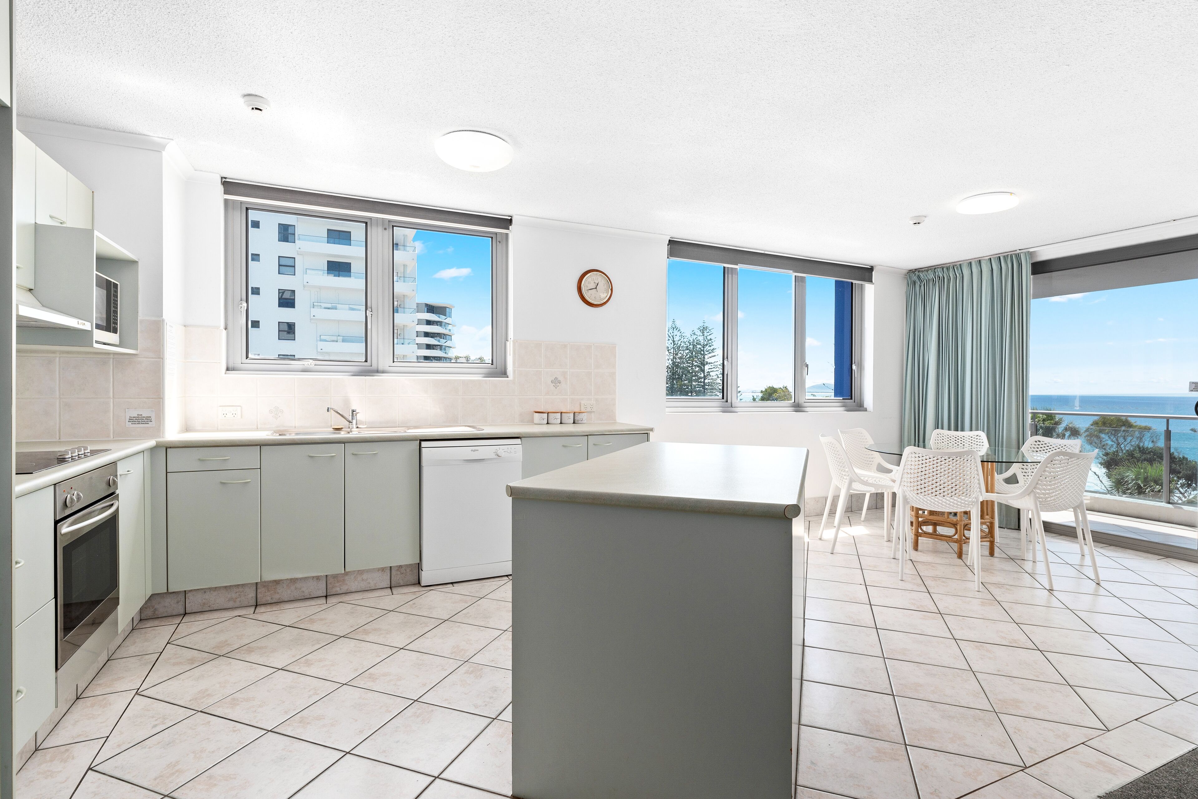 Une cuisine moderne dotée d’un îlot central, de grandes fenêtres et offrant une vue sur la mer.